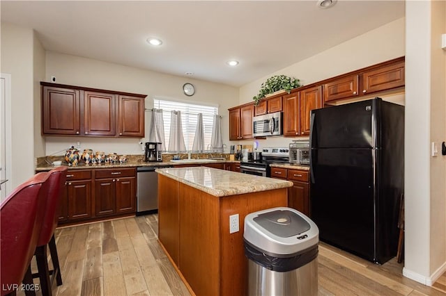 kitchen featuring stainless steel appliances, light wood finished floors, a kitchen island, and recessed lighting