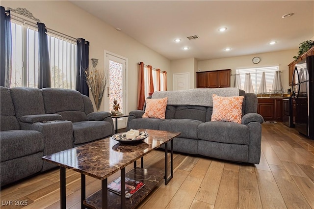 living area with light wood finished floors, visible vents, and recessed lighting