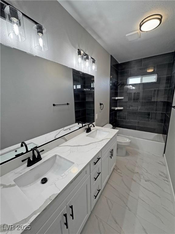 full bathroom with toilet, marble finish floor, double vanity, and a sink