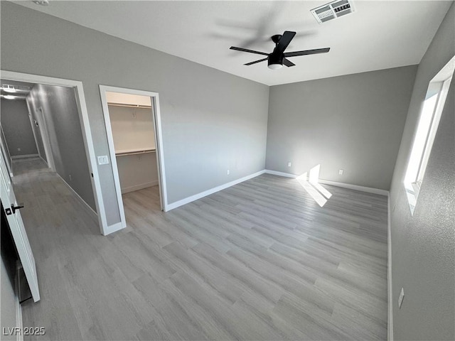 unfurnished bedroom featuring visible vents, baseboards, light wood-style floors, a spacious closet, and a closet