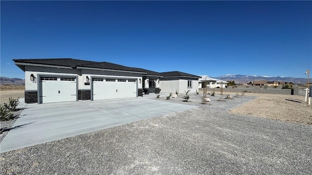 view of front of property featuring an attached garage, stone siding, a mountain view, and concrete driveway