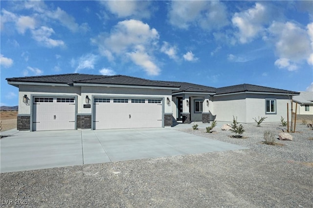 prairie-style house featuring stone siding, driveway, an attached garage, and stucco siding