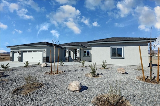 view of front of house with an attached garage, driveway, and stucco siding