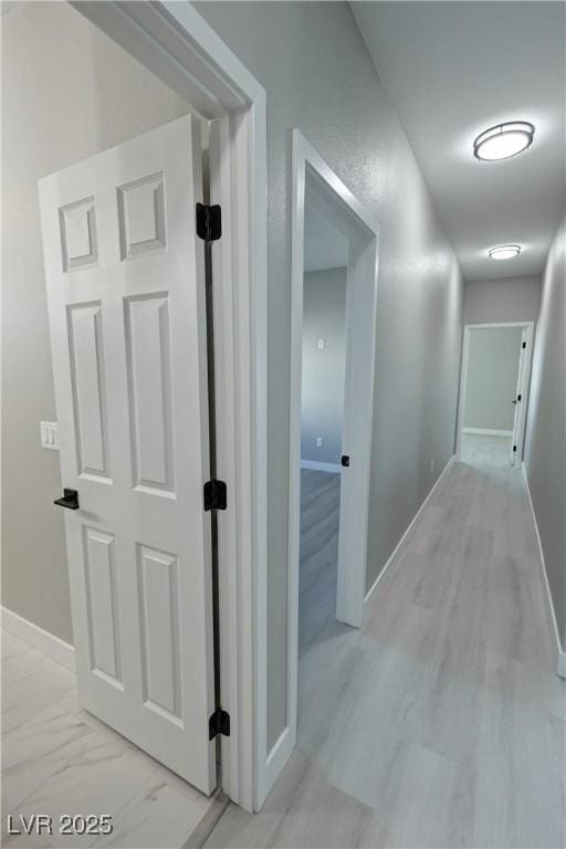 hallway featuring marble finish floor and baseboards