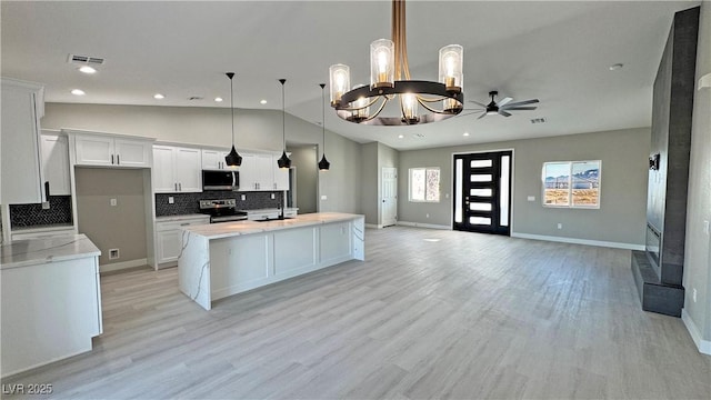 kitchen featuring visible vents, hanging light fixtures, appliances with stainless steel finishes, open floor plan, and white cabinets