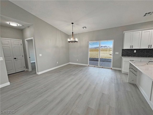 unfurnished dining area with a chandelier, visible vents, light wood-style flooring, and baseboards