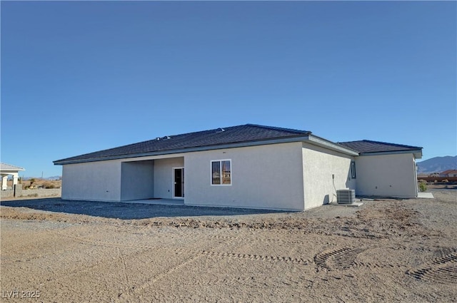 rear view of property with cooling unit and stucco siding