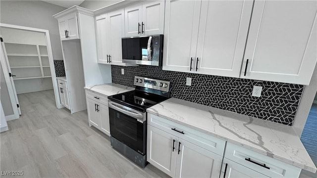 kitchen featuring decorative backsplash, appliances with stainless steel finishes, light wood-style floors, white cabinets, and light stone countertops