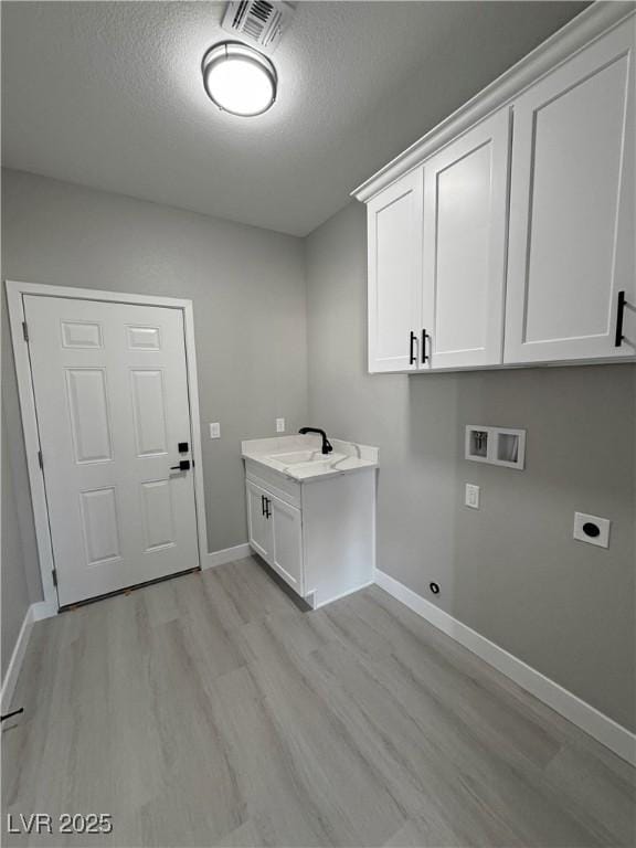 clothes washing area featuring washer hookup, hookup for an electric dryer, cabinet space, and light wood finished floors