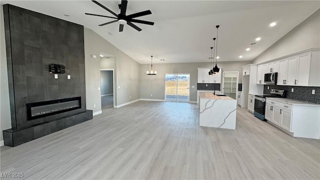 kitchen with white cabinets, pendant lighting, stainless steel appliances, and open floor plan