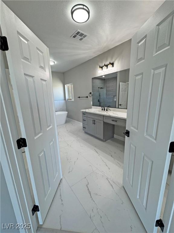 bathroom with visible vents, vanity, marble finish floor, a textured ceiling, and a freestanding bath