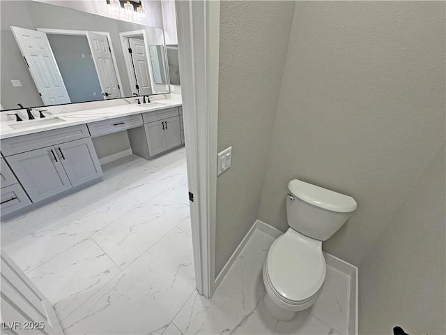 bathroom with double vanity, marble finish floor, and a sink