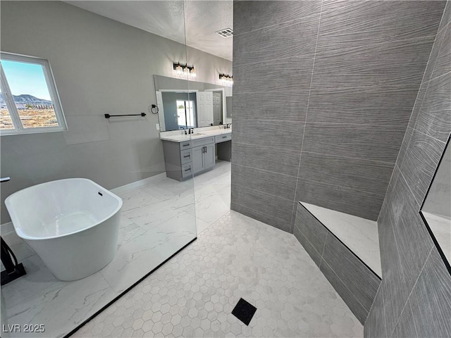 full bath with visible vents, vanity, baseboards, marble finish floor, and a soaking tub