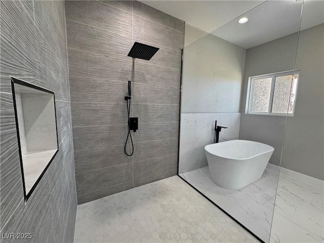 bathroom featuring a soaking tub, marble finish floor, a walk in shower, tile walls, and recessed lighting