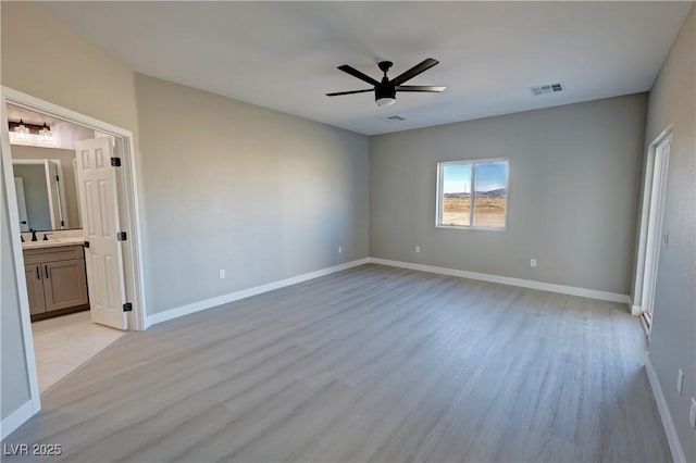 unfurnished bedroom with light wood finished floors, a sink, visible vents, and baseboards