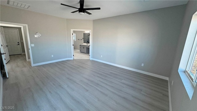 unfurnished bedroom featuring ensuite bathroom, light wood-style flooring, visible vents, and baseboards