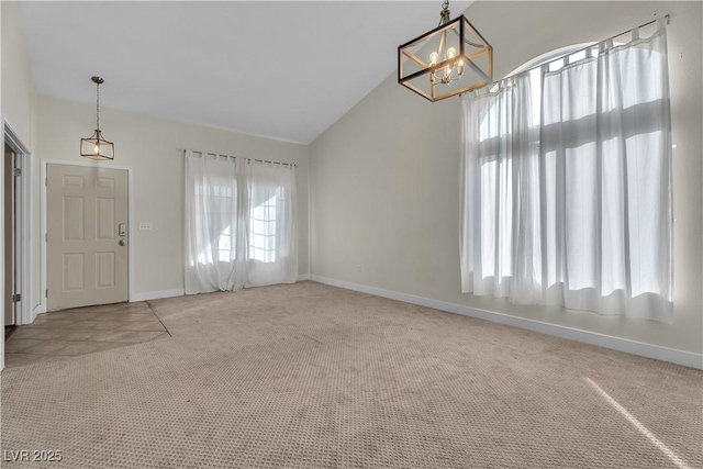 carpeted foyer with an inviting chandelier and high vaulted ceiling