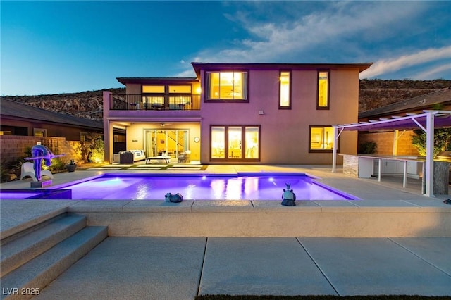 pool at dusk featuring a bar, a patio area, and area for grilling