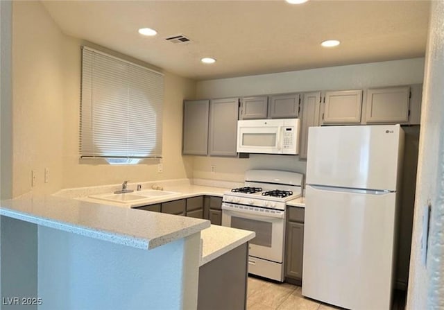 kitchen with light tile patterned flooring, sink, gray cabinetry, kitchen peninsula, and white appliances