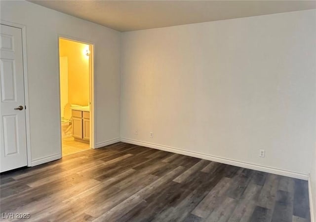 unfurnished bedroom with connected bathroom and dark hardwood / wood-style floors