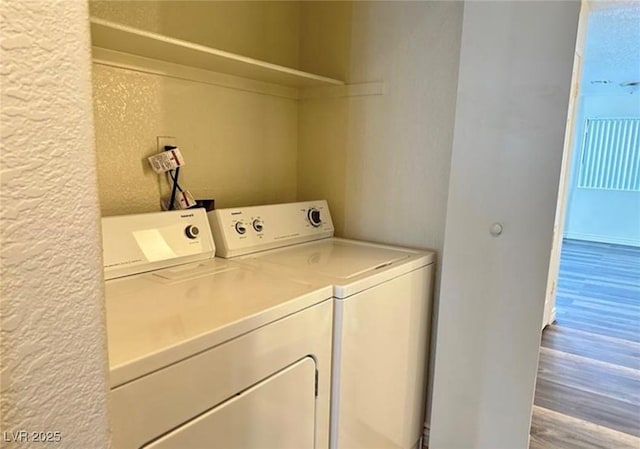 clothes washing area featuring hardwood / wood-style floors and washer and clothes dryer