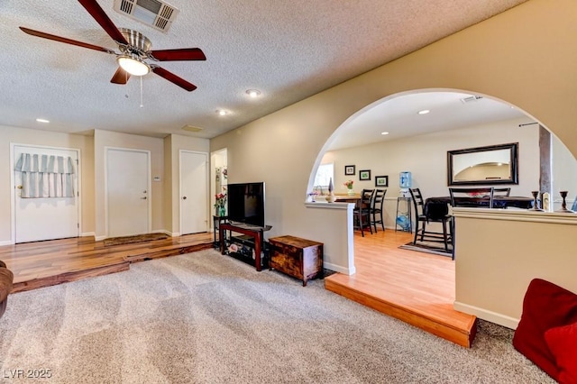 living room with ceiling fan, a textured ceiling, and carpet