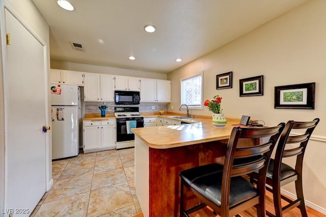 kitchen featuring white fridge, sink, white cabinets, and gas range oven