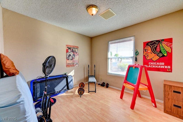 workout room featuring hardwood / wood-style floors and a textured ceiling