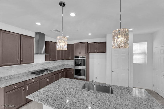 kitchen with hanging light fixtures, stainless steel appliances, sink, and wall chimney exhaust hood