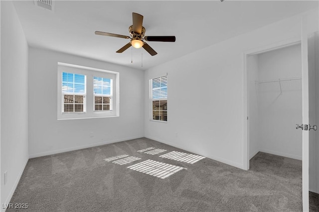 unfurnished bedroom with light carpet, a walk in closet, a closet, and ceiling fan