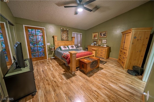 bedroom with lofted ceiling, a textured ceiling, and light hardwood / wood-style floors