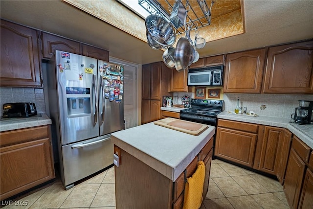 kitchen featuring a kitchen island, backsplash, light tile patterned floors, a tray ceiling, and stainless steel appliances