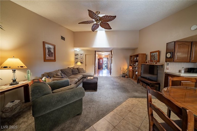 living room with lofted ceiling, light carpet, a textured ceiling, and ceiling fan