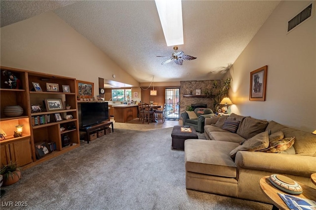 living room with a stone fireplace, high vaulted ceiling, a textured ceiling, carpet floors, and ceiling fan