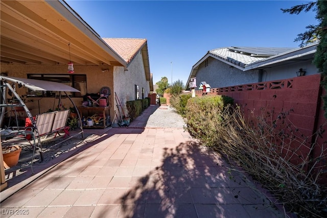 view of side of property with a patio area and solar panels