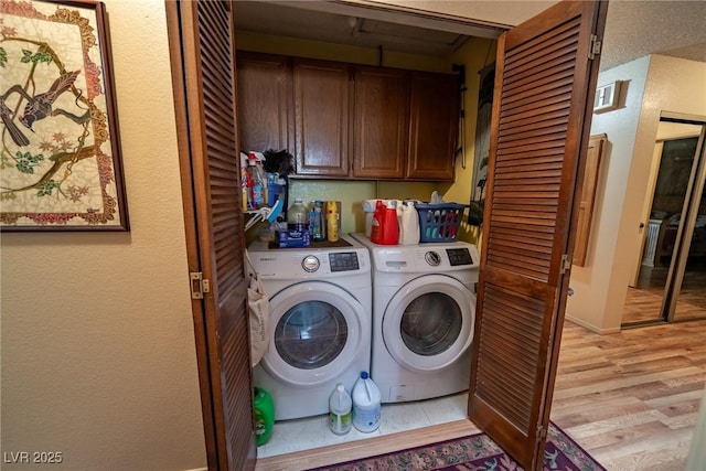 laundry room featuring cabinets, washer and clothes dryer, and light wood-type flooring