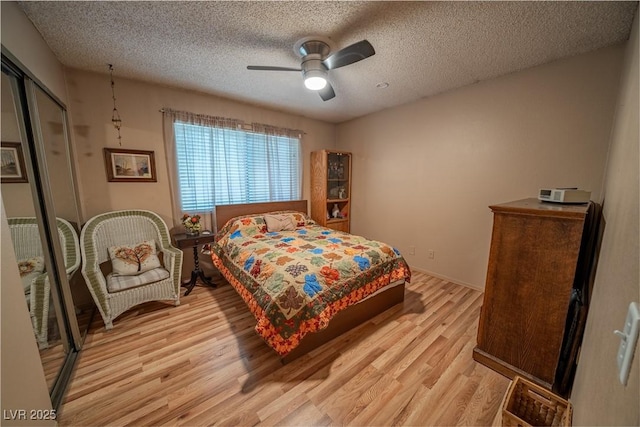 bedroom with ceiling fan, light hardwood / wood-style flooring, and a textured ceiling