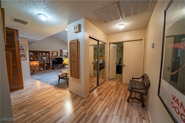 hall with a textured ceiling and light wood-type flooring