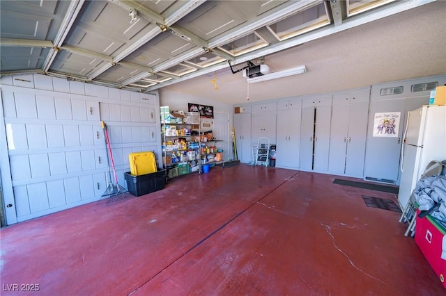 garage with a garage door opener and white refrigerator