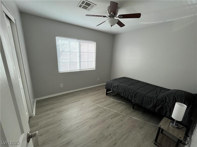 bedroom featuring wood finished floors, visible vents, baseboards, a ceiling fan, and a closet