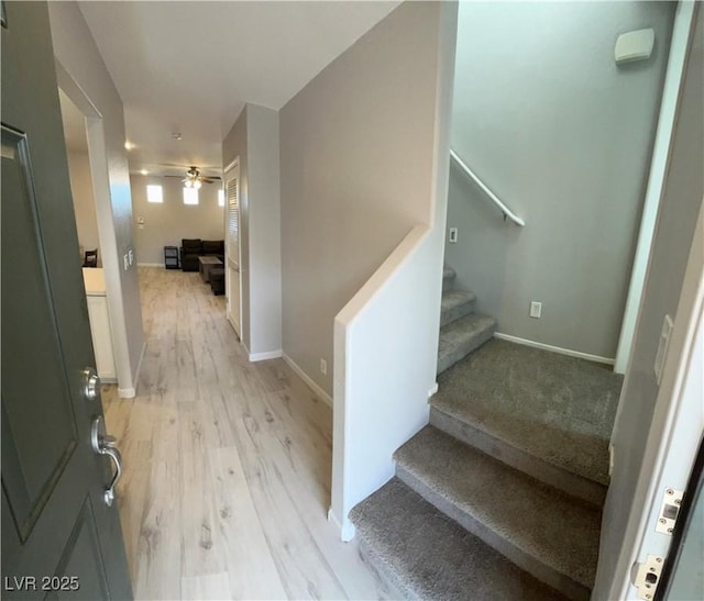 staircase with ceiling fan, baseboards, and wood finished floors