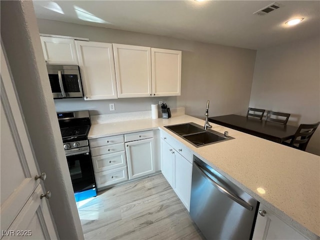 kitchen with stainless steel appliances, white cabinetry, and sink