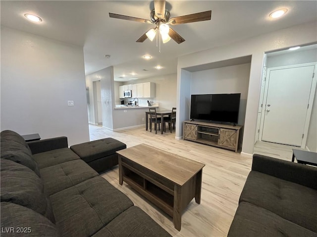 living room featuring light wood-style floors, ceiling fan, baseboards, and recessed lighting