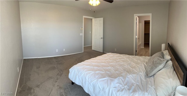 bedroom with dark colored carpet, a spacious closet, and ceiling fan