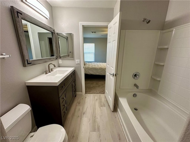 ensuite bathroom with ensuite bathroom, bathtub / shower combination, toilet, wood finished floors, and vanity