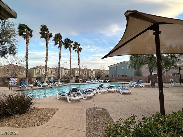 community pool featuring a patio area, fence, and a residential view