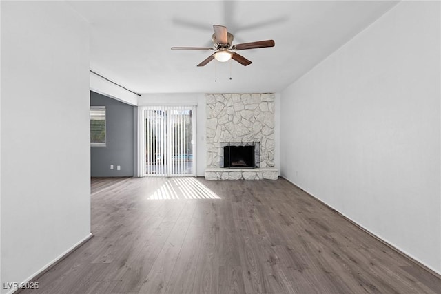 unfurnished living room with ceiling fan, wood-type flooring, and a stone fireplace