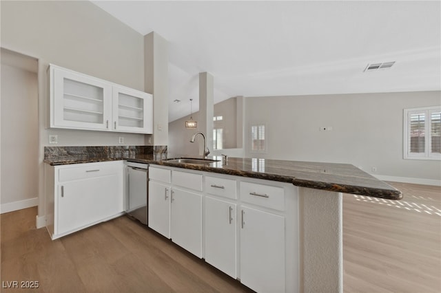 kitchen with lofted ceiling, sink, white cabinetry, light wood-type flooring, and kitchen peninsula