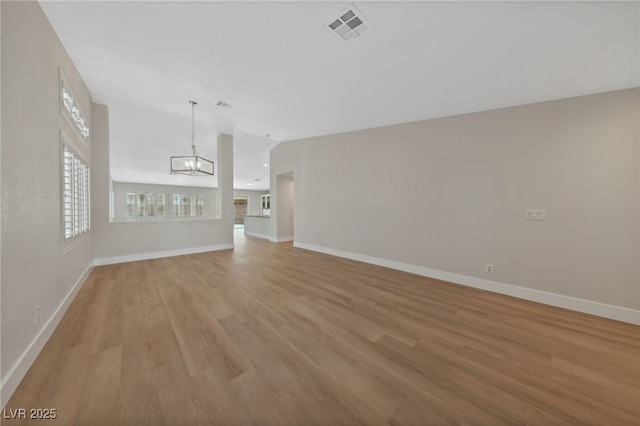 unfurnished living room featuring lofted ceiling, light hardwood / wood-style flooring, and a chandelier