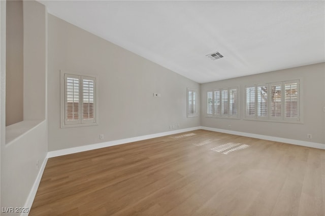 spare room with vaulted ceiling and light wood-type flooring